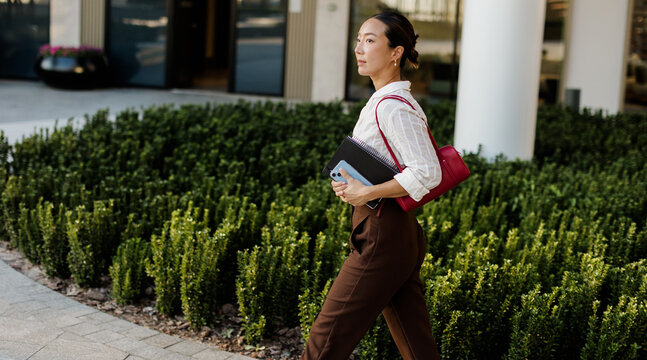 Korean woman walks confidently through a modern urban garden setting