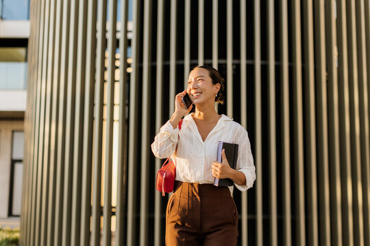 Korean woman enjoys a sunny day while chatting on the phone outside