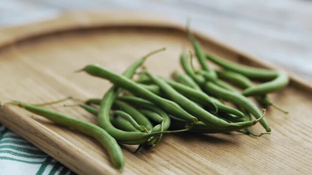 Freshly washed organic green beans on a wooden cutting board, food prep