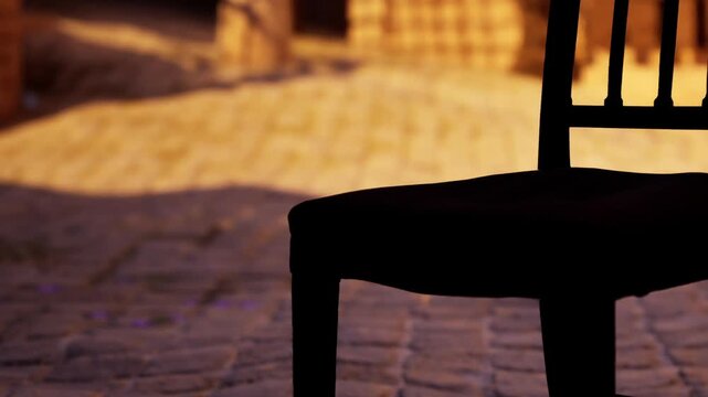 A chair sits alone on a cobblestone street as the sun sets. The warm light creates shadows around the chair, hinting at an idle moment. No people are present in the scene.