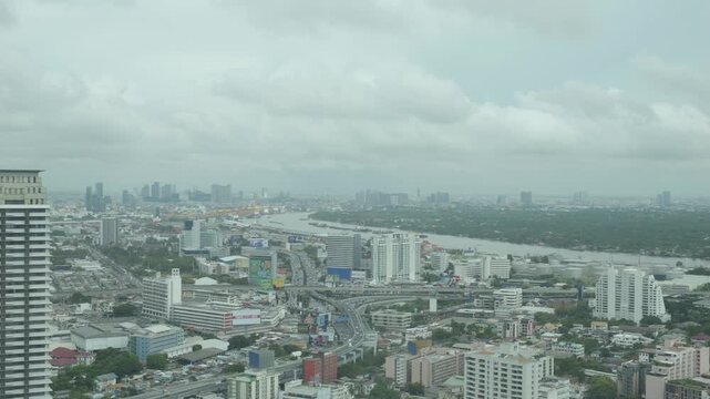 This aerial image captures a bustling urban landscape featuring a prominent waterway, surrounded by buildings and vegetation under a cloudy sky. The dynamic arrangement of structures showcases the ble