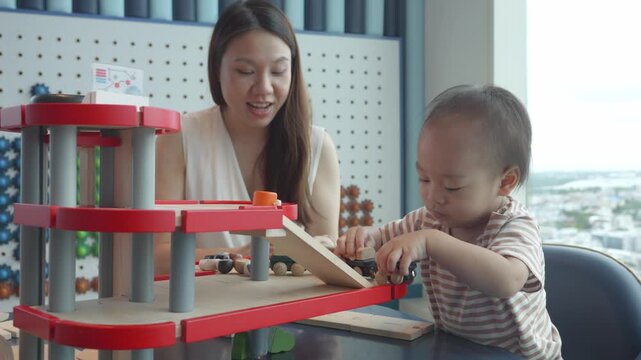 A caregiver and child share quality time, playing with a wooden toy set. The scene captures the joy of learning through play in a bright, modern space, encouraging creativity and skill development in 