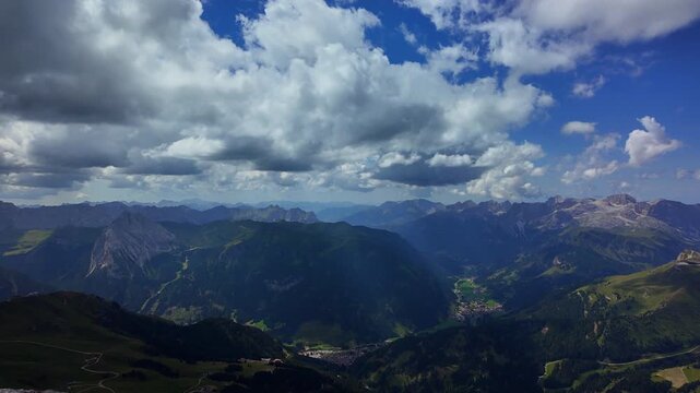 Panoramic view over the alpine valley and Sass Pordoi mountain pass in the Dolomites under a dramatic cloudy sky