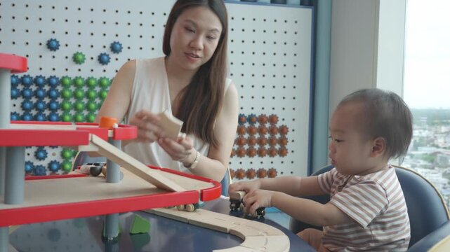 A joyful moment captured as a mother and her child engage in play with colorful toys, fostering creativity and bonding in a bright, inviting space.