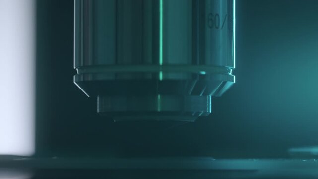 Extreme close-up of microscope objective lens surface with sweeping light reflection