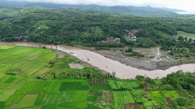 Aerial view of Lio citarik river winding through lush green rice paddies and hills in Kecamatan Pelabuhanratu, Jawa Barat, Indonesia.