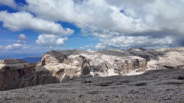 Pan view of the rocky plateau of Sass Pordoi in the Sella Group Dolomites under a blue cloudy sky