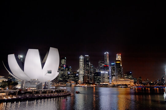 Singapore skyline at night with illuminated buildings and waterfront reflections.