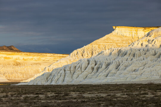 View of the white limestone cliffs of Tuzbair salt flats under a dramatic stormy sky in Mangystau District, Mangystau Region, Kazakhstan.