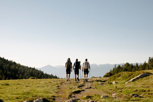 three Friends hiking toward mountain view at sunrise in the Pyrenees