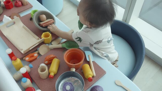 A young child explores their imagination with an assortment of colorful toy foods and kitchen tools, fostering creativity and play. This scene captures the joy and learning involved in imaginative pla