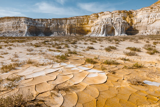 View of the dramatic white limestone cliffs and cracked dry earth of the Tuzbair salt flats in Mangystau District, Mangystau Region, Kazakhstan.
