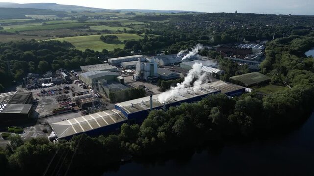 Aerial view of industrial facility with smoking chimneys situated by the river in Lancaster, England, United Kingdom.