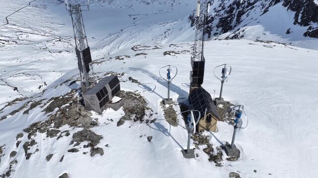 Aerial view of the Trollstigen mountain station featuring wind turbines, solar panels, and communication towers set against a vast snowy landscape in Valldal, More og Romsdal, Norway.