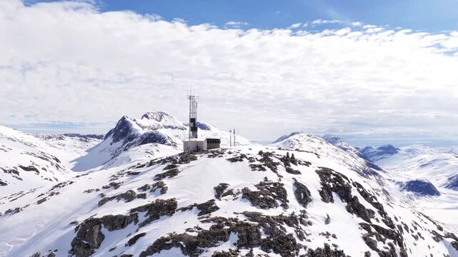Aerial view of the communication tower atop the snow-covered Trollstigen mountain peak in Valldal, More og Romsdal, Norway.