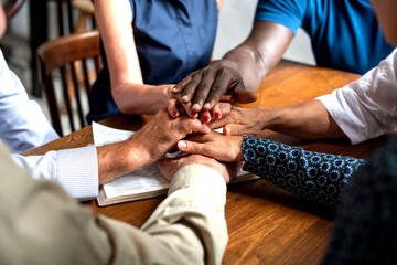 Obraz premium Diverse group of hands joined together over a wooden table.