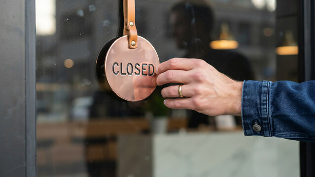 Hand Turning Round Copper Closed Sign on Store Glass Door