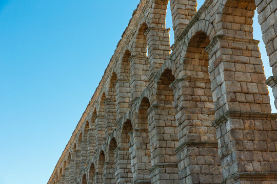 Low-angle view of the Roman aqueduct in Segovia against blue sky