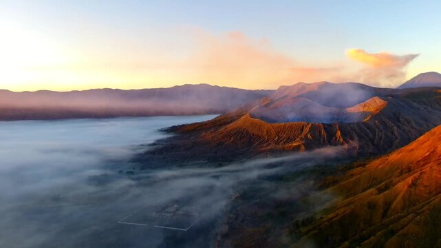 Aerial view of Mount Bromo with volcanic crater and sea of clouds at sunrise in Tosari, East Java, Indonesia.