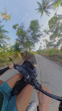 Helmeted Man Rides a Scooter Along a Palm Lined Rural Road, Captured With a Little Planet View, Showing Tropical Travel and Adventure Vertical video.
