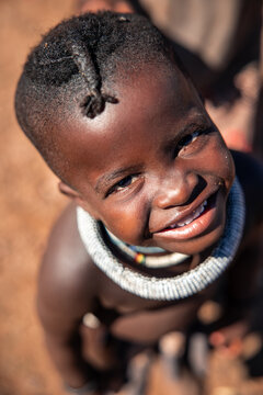Himba child smiling wearing traditional necklace in Namibia