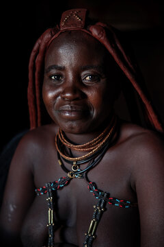 Himba woman smiling wearing traditional otjize and jewelry in Namibia