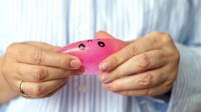 Women hands squeezes a pink squishing stress toy in close-up. Concept of tactile stimulation, stress relief, emotional regulation and sensory coping during a digital work break.