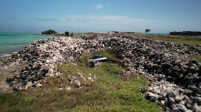 Aerial view of a large pile of conch shells on the coast of the Los Roques archipelago with turquoise sea and clear sky in Los Roques, Dependencias Federale, Venezuela.