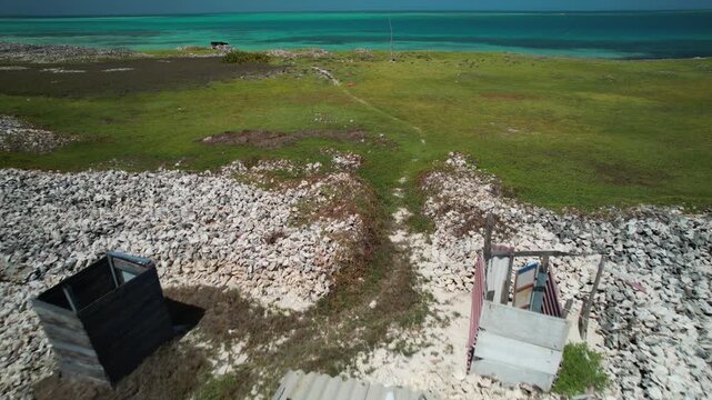 Aerial view of Los Roques archipelago with small wooden structures and piles of conch shells on the sandy beach in Los Roques, Dependencias Federales, Venezuela.