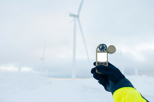 Measuring wind speed with a handheld anemometer at a wind farm in winter