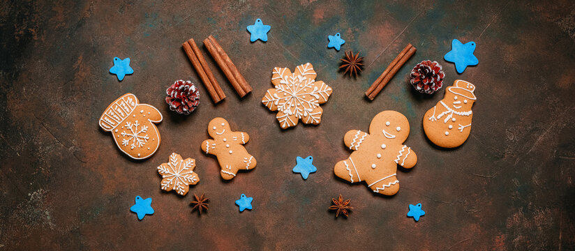 Christmas homemade gingerbread cookies on dark rustic background, gingerbread man, snowman, mitten, snowflakes, top view, flat lay, banner