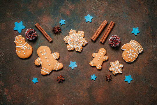 Christmas gingerbread cookies with spices and blue wooden stars on dark grunge background, gingerbread men, top view, flat lay.