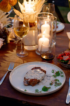 Romantic candlelit dinner featuring a steak topped with creamy mushroom sauce, wine glasses, soft candle glow and elegant table decor for an intimate evening or gourmet restaurant meal