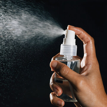  A hand using a spray bottle watering something  with black background