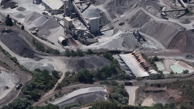 High aerial of quarry processing plant stockpiles conveyors roads and green vegetation patches