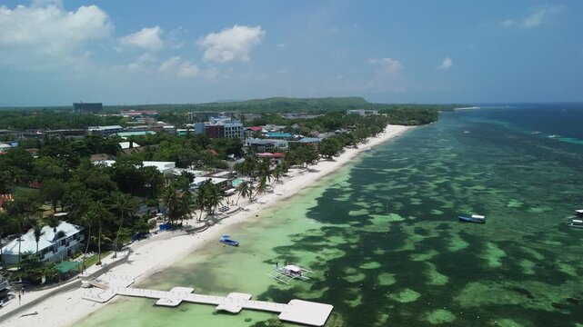 Aerial view of Alona Beach with white sand, turquoise water, and boats along the coastline in Panglao, Bohol, Philippines.