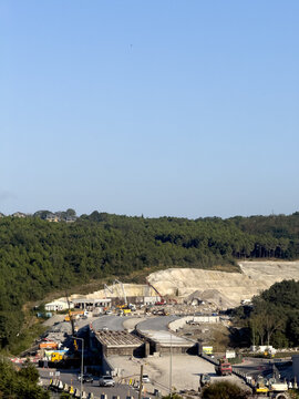 View of road construction site with heavy machinery, excavators, and trucks working on a new highway project surrounded by green forested hills in Sariyer, Istanbul, Turkiye.