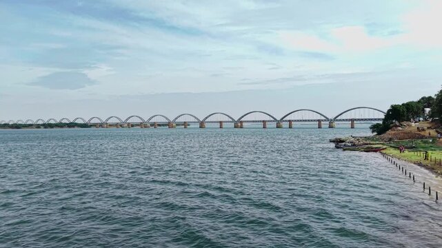 Aerial view of the iconic Godavari Arch Bridge spanning the river with lush green banks and calm water in Rajahmundry, Andhra Pradesh, India.
