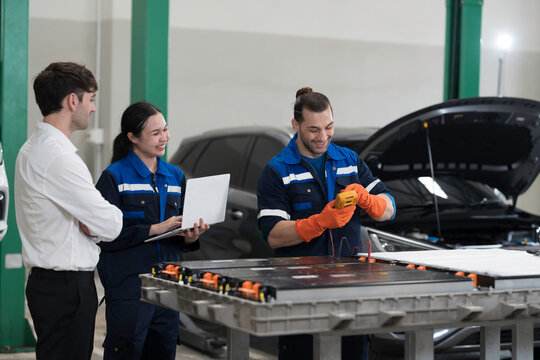 Electric vehicle car auto services. EV garage. Diagnostic battery pack. Customer and mechanic discussion and diagnosing electric car vehicles battery, component checks at auto workshop