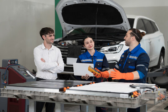 Electric vehicle car auto services. EV garage. Diagnostic battery pack. Customer and mechanic discussion and diagnosing electric car vehicles battery, component checks at auto workshop