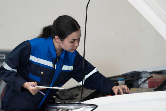 Female mechanic working at the garage. Female car mechanic examining, repair and maintenance under hood of car at auto car repair service. Car service and Maintenance concept