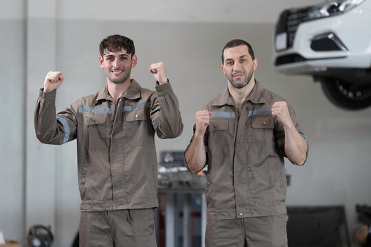 Electric vehicle car auto services, EV garage. Team of mechanic standing wear work uniform in auto workshop