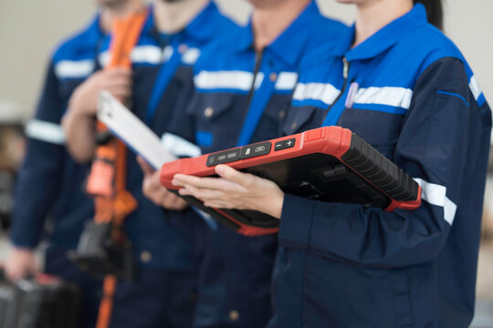 Electric vehicle car auto services, EV garage. Team of mechanic and electrician standing wear work uniform and holding equipment tools for work in auto workshop