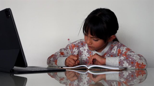 Young girl learning online with a digital tablet and notebook