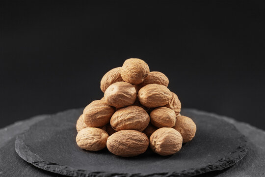 whole nutmeg seed from the Myristica fragrans tree on a black slate stone tray