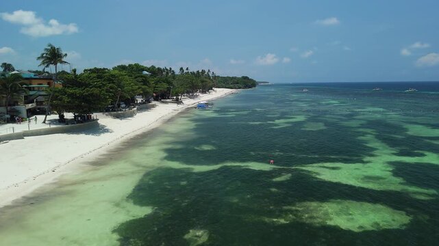 Aerial view of Alona Beach with white sand, palm trees, and clear turquoise waters in Panglao, Bohol, Philippines.