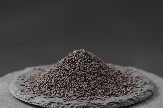 black cumin seeds of the dried plant nigella sativa on a black slate stone tray