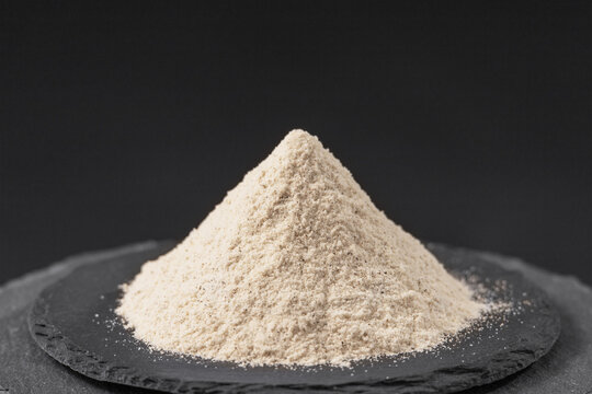 white seeds pepper powder of ripe piper nigrum fruits on a black slate stone tray