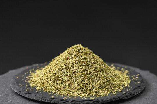 thyme leaf flakes from the plant Thymus vulgaris on a black slate stone tray