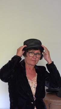A woman is trying on a black retro hat at home. vertical video.